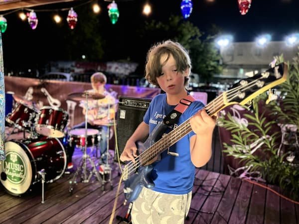 Band member playing bass guitar at night