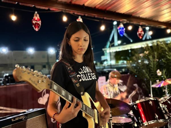 Band member playing electric guitar under string lights