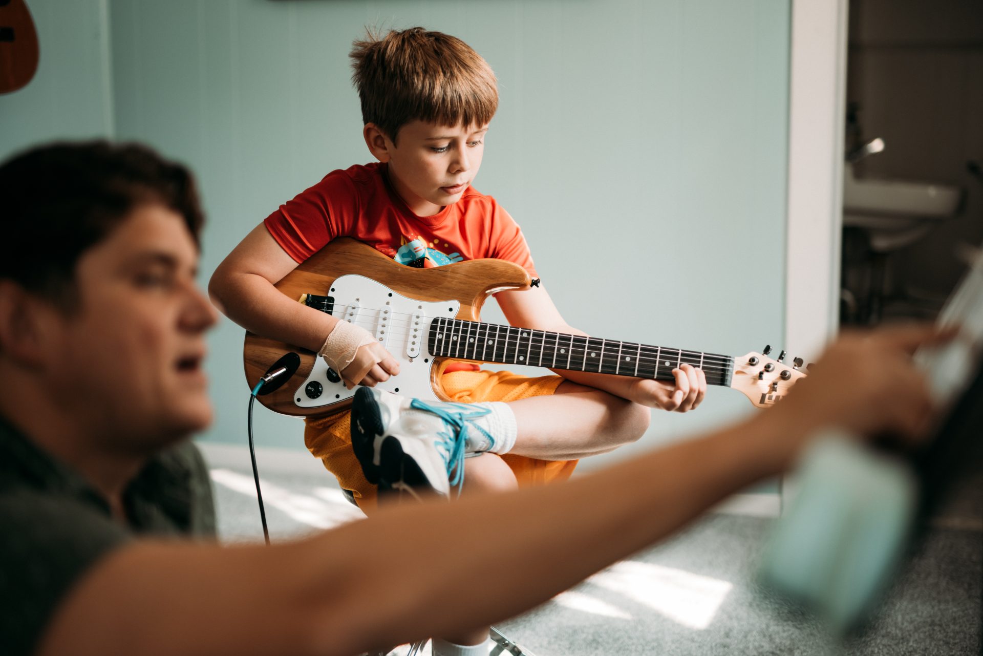 child playing guitar with instructor