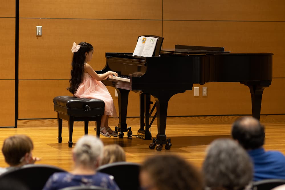 Young girl playing a piano recital.