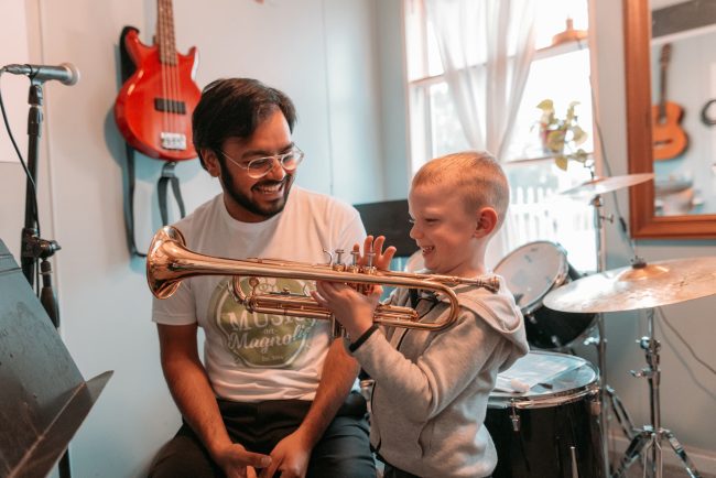 kid playing trumpet with teacher