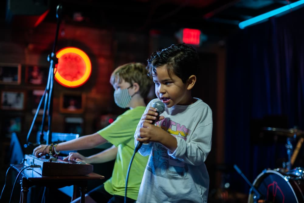 Young boy singing on stage.