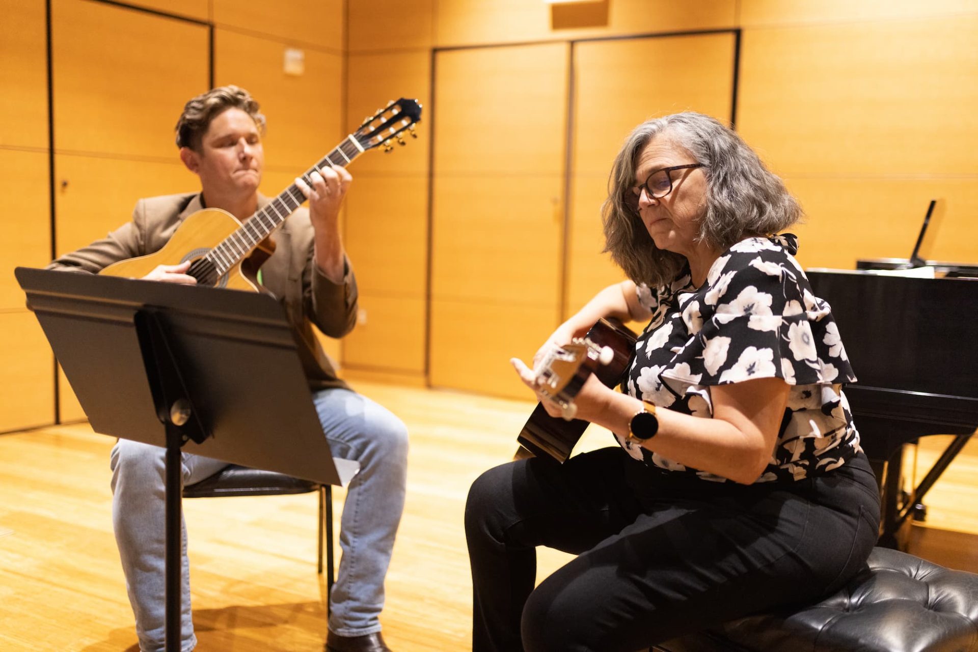 Adult performing on stage playing guitar with their instructor